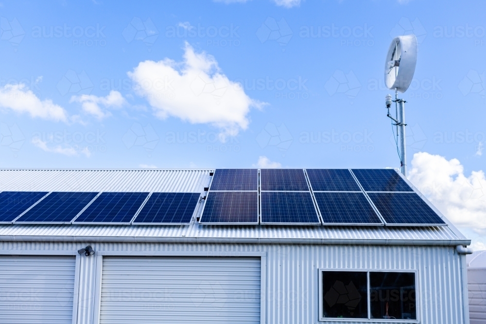 off grid sustainable living with solar panels and wind turbine on shed roof - Australian Stock Image