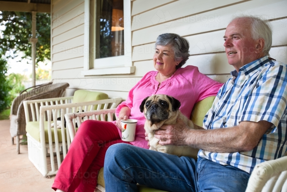 Old couple sitting on the front porch with their pet dog - Australian Stock Image