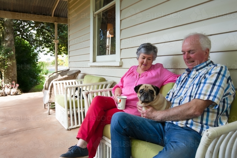 Old couple sitting on the front porch with their pet dog - Australian Stock Image