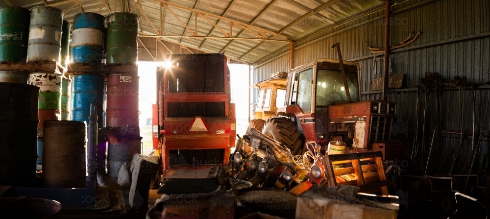 Old farm machinery parked in dark shed left to rust and forgotten in time - Australian Stock Image