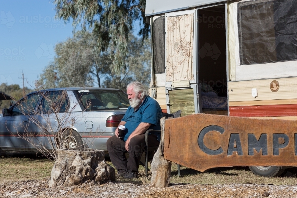 Old guy sitting outside his vintage pop-up caravan - Australian Stock Image