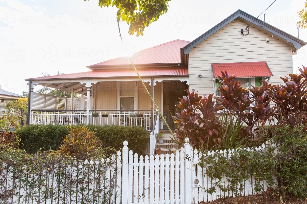 old Queenslander style house in Brisbane suburbs with an overgrown garden on a sunny day - Australian Stock Image