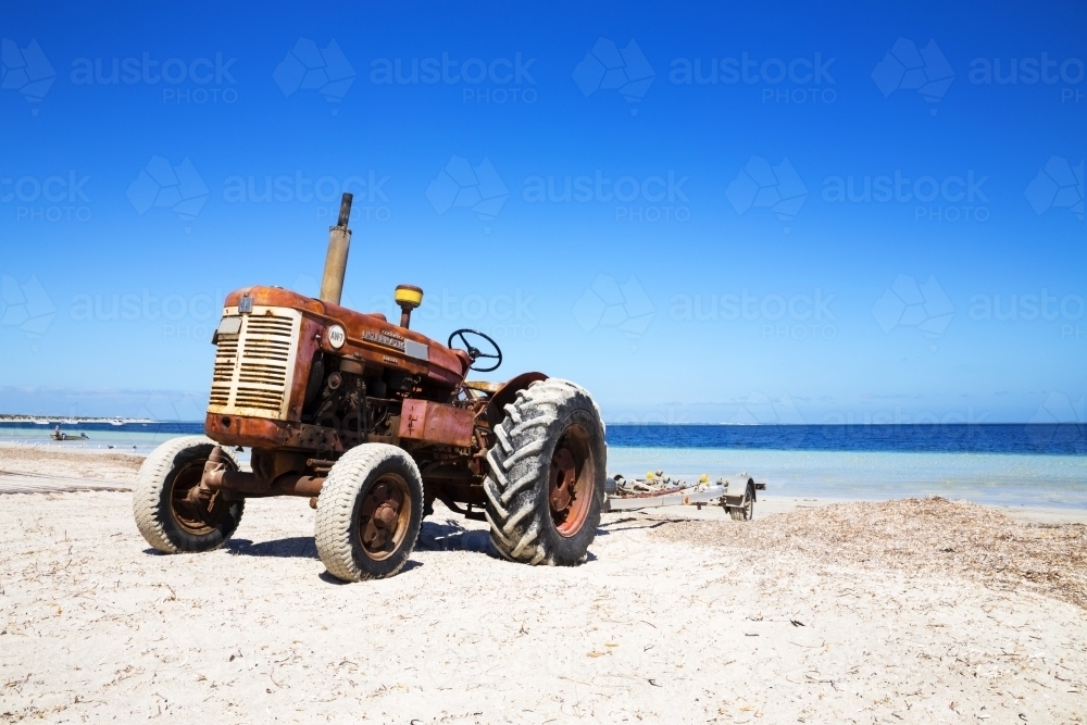 Old tractor on beach with boat trailer - Australian Stock Image