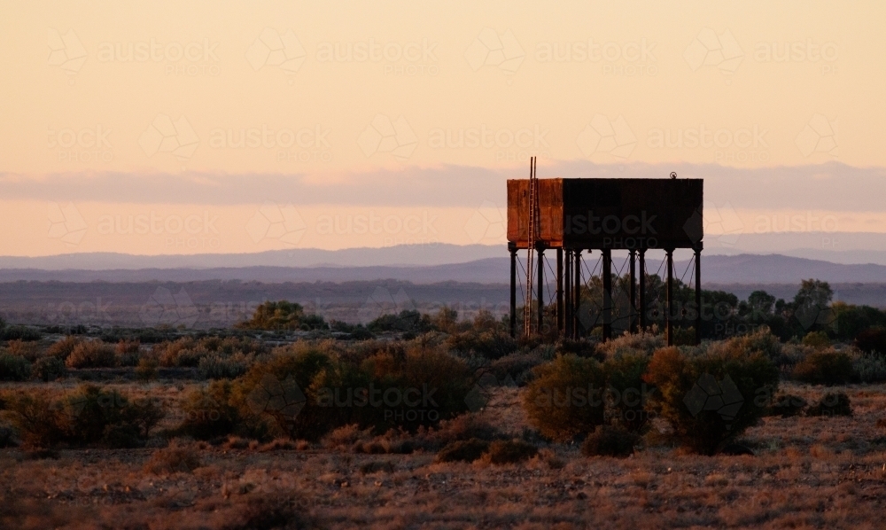 old water tank at sunrise with hills in background - Australian Stock Image