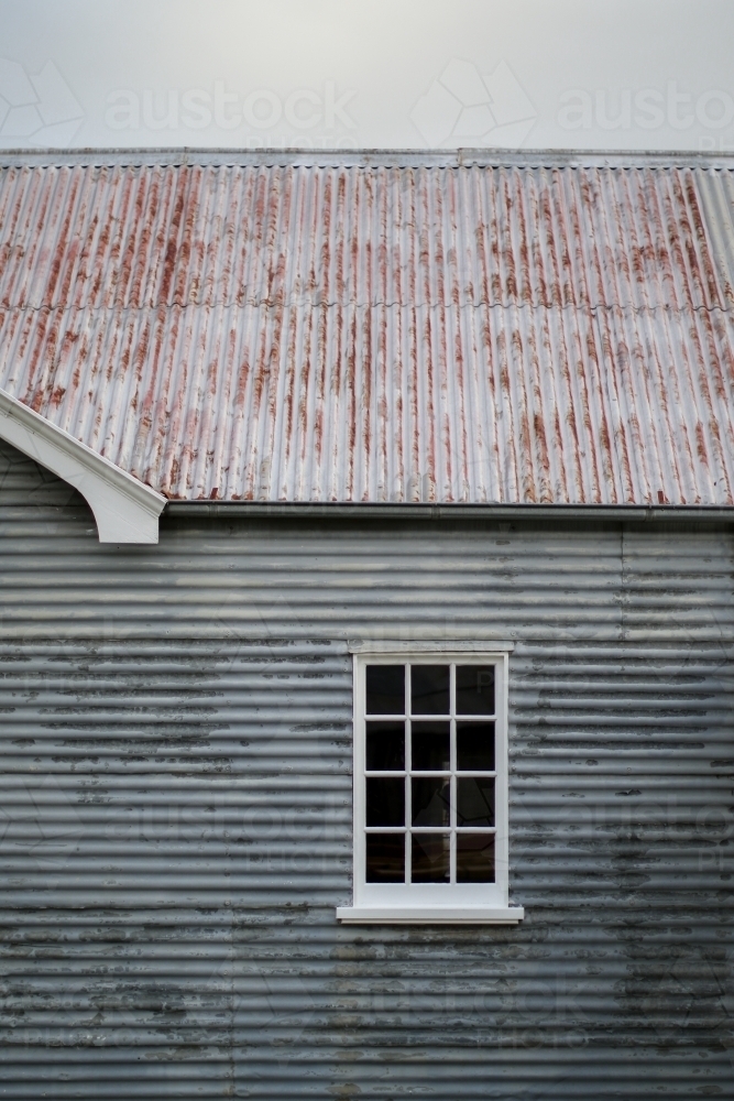 Old weathered corrugated iron farm shed with restored glass window - Australian Stock Image