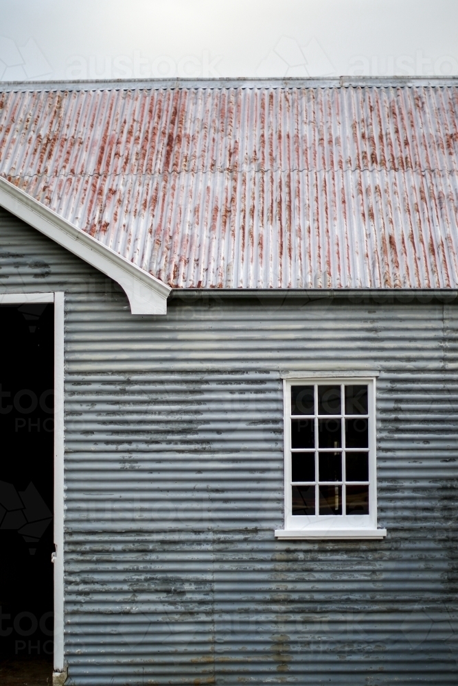 Old weathered corrugated iron farm shed with restored glass window - Australian Stock Image