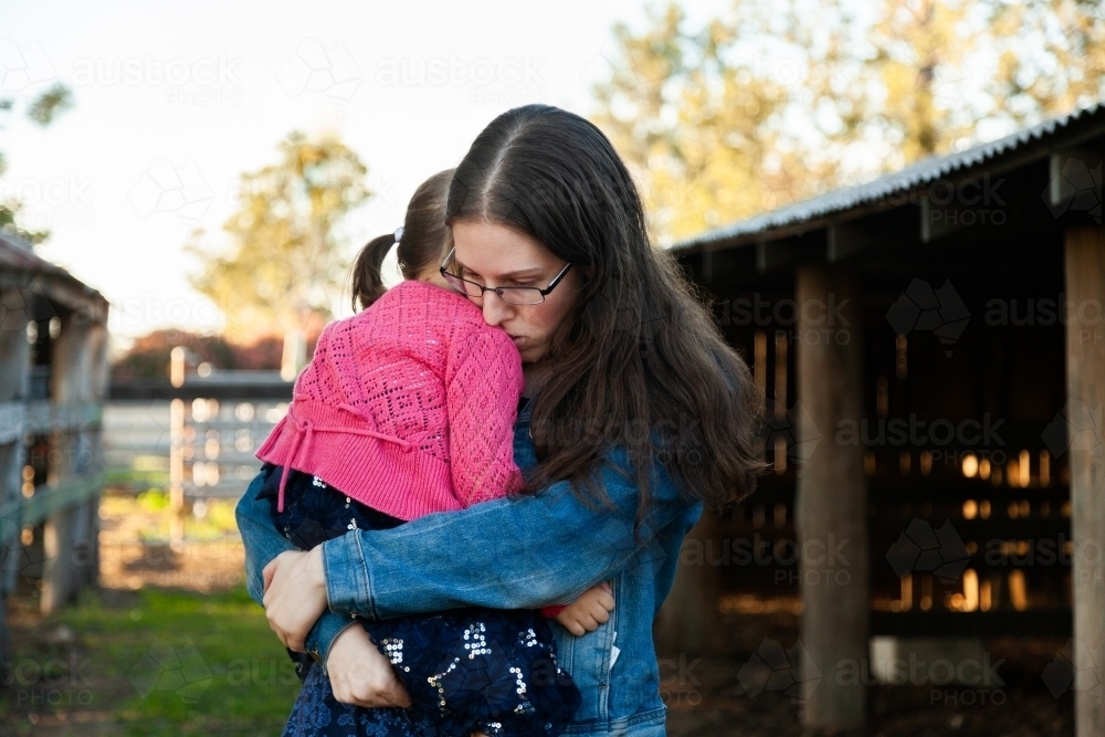 Older sister comforting little sister with hug - Australian Stock Image