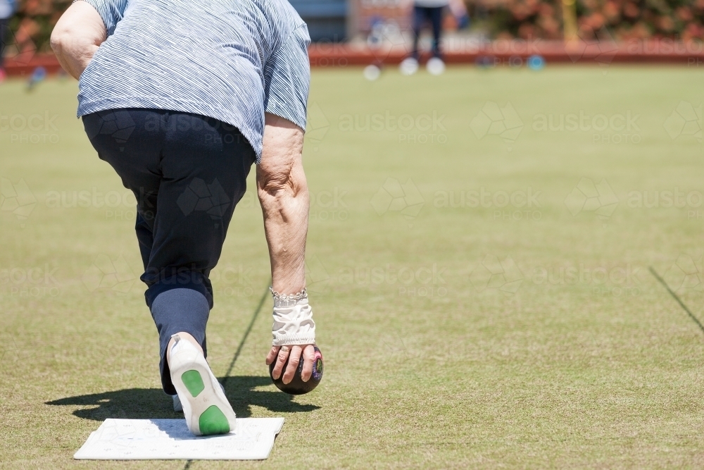 Older woman delivering a lawn bowl - Australian Stock Image