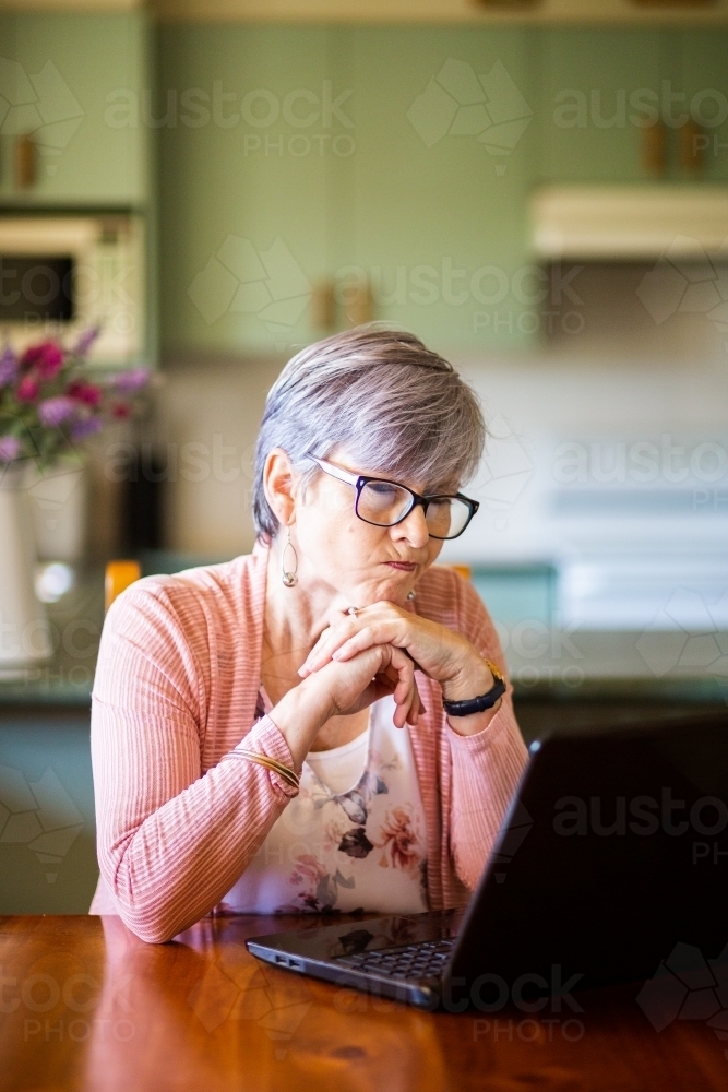 Older woman struggling using laptop technology - Australian Stock Image