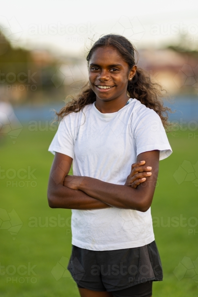 one aboriginal girl standing with arms crossed and looking at the camera - Australian Stock Image