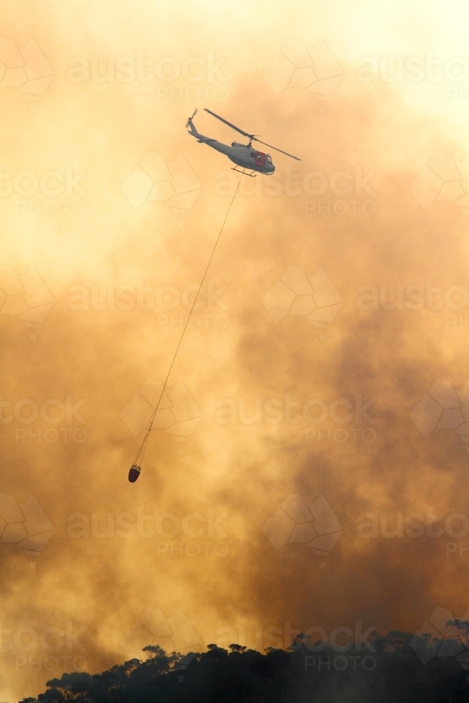 One fire fighting helicopter dumping water onto a bushfire on Maddens Plains, Illawarra, NSW - Australian Stock Image