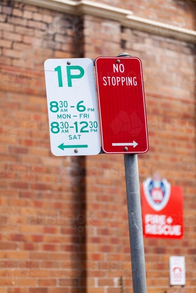 one hour parking and no stopping warning street sign near fire and rescue station - Australian Stock Image