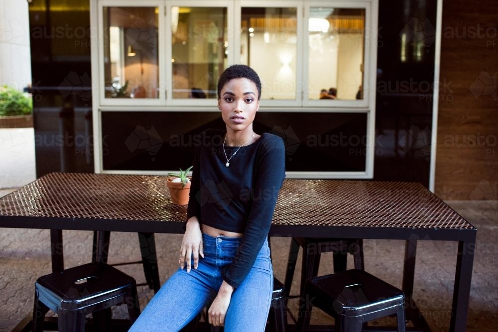 One woman sitting outside at a cafe table - Australian Stock Image