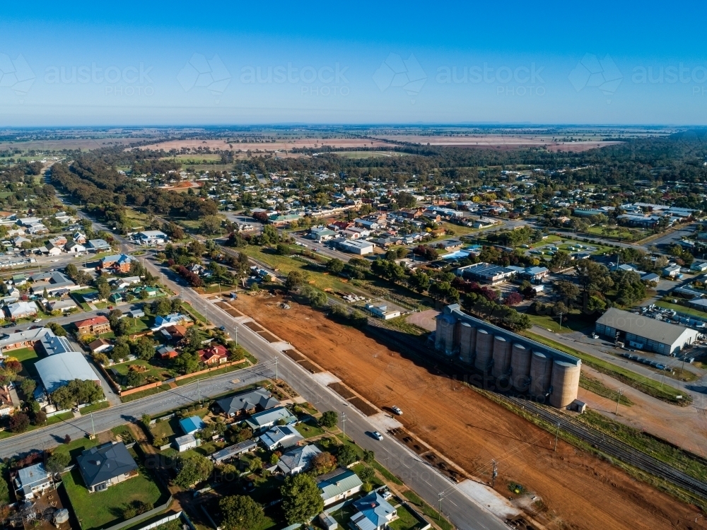 Orange red dirt dividing grain silos from streets and houses in country town in NSW Australia - Australian Stock Image
