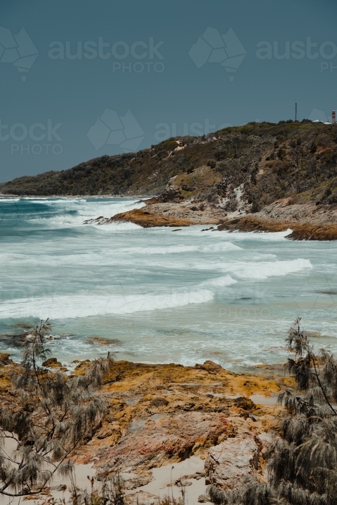 Orange rocks and blue ocean at Honeymoon bay, Moreton Island - Australian Stock Image