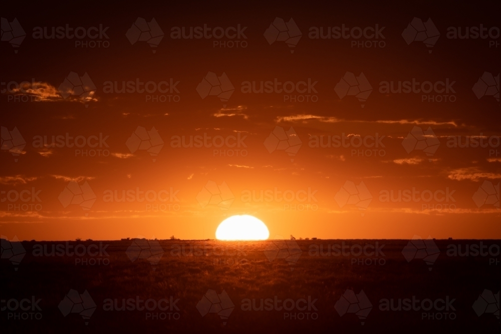 Orange sun setting over rural landscape - Australian Stock Image