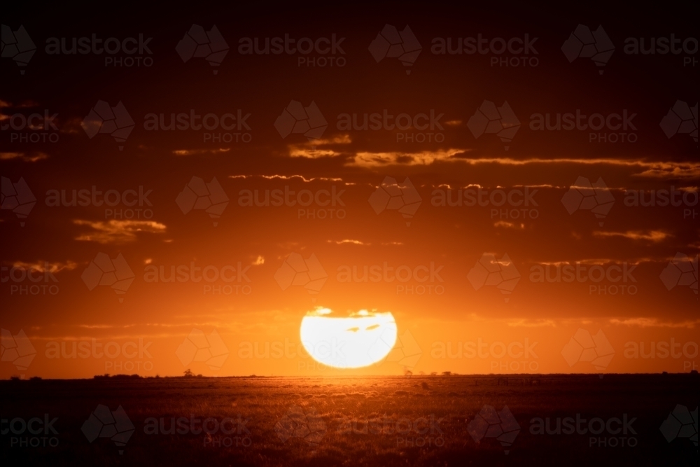 Orange sun setting over rural landscape - Australian Stock Image