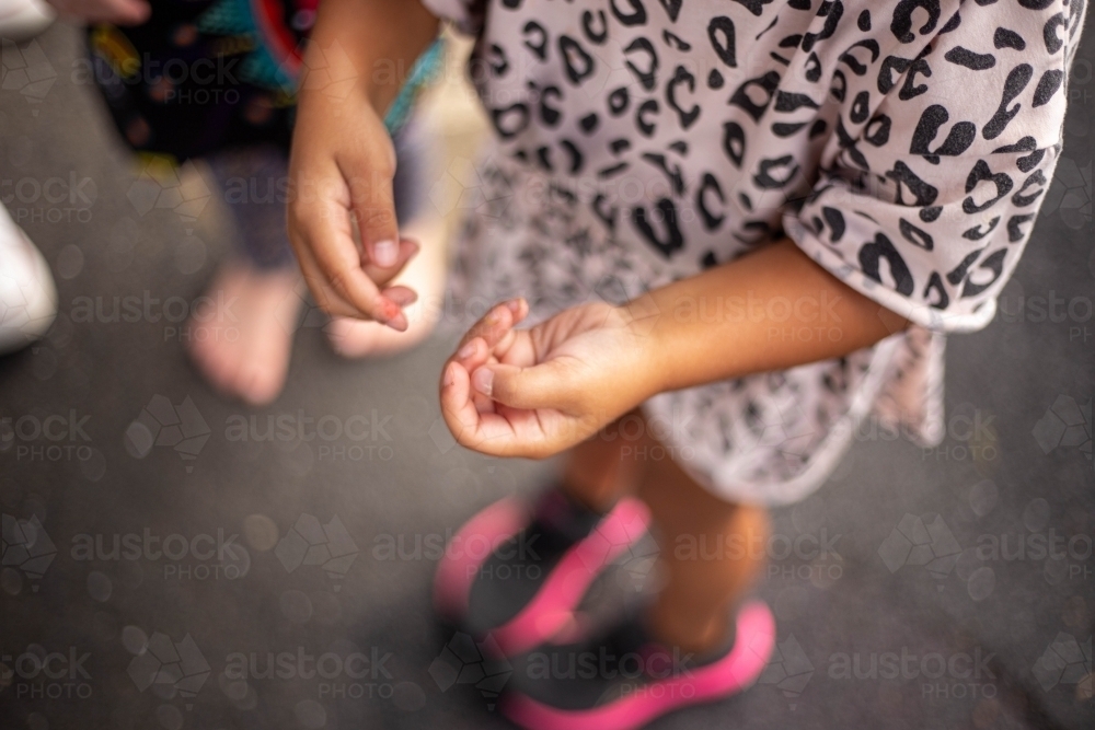 Out of focus hands of a young Aboriginal girl at preschool - Australian Stock Image