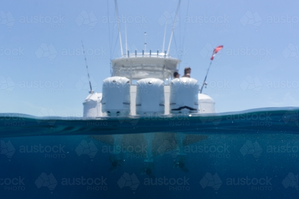 Out of focus luxury boat with large outboards floating in deep blue water - Australian Stock Image