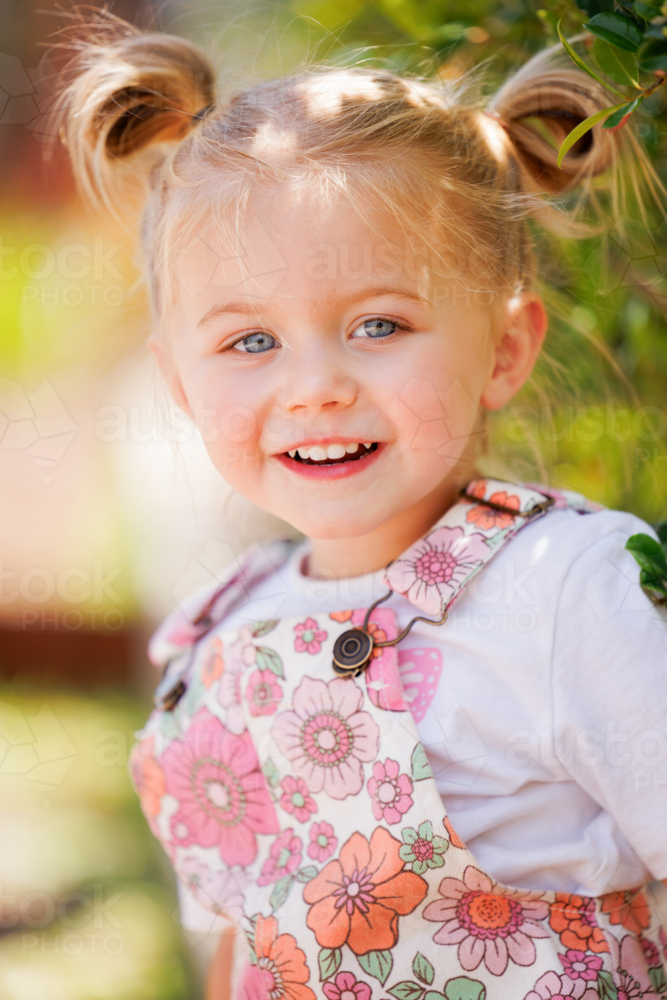 out of focus preschool child sitting on edge of garden bed in bright sunny kindergarten yard - Australian Stock Image