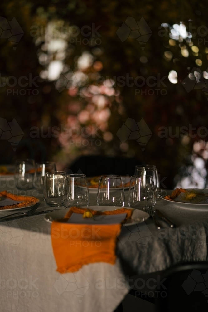 Outdoor dining table with wine glasses, plates, and cutleries - Australian Stock Image