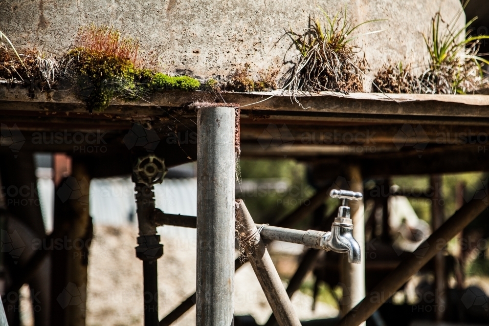 Outside tap on a moss covered concrete tank stand - Australian Stock Image