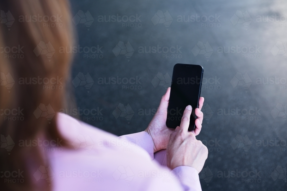 Over the shoulder shot of woman typing on mobile phone - Australian Stock Image