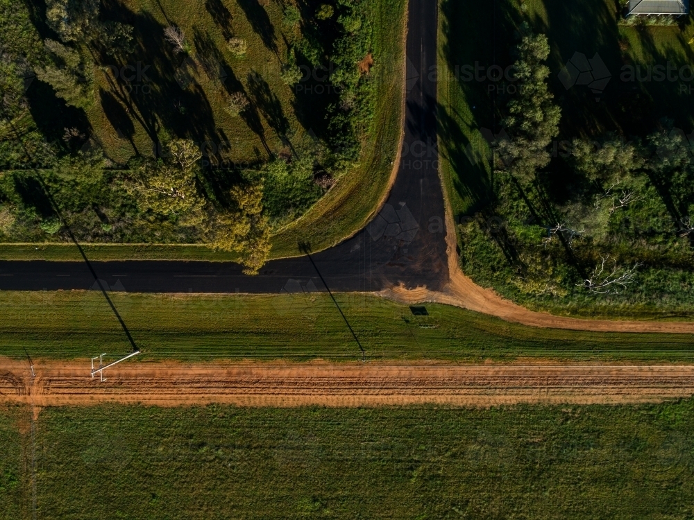 Overhead aerial view of right angled bend in country road beside farmland - Australian Stock Image