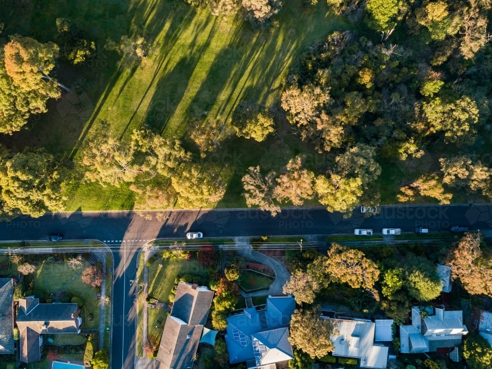 Overhead aerial view of t intersection in city suburb with houses and parkland - Australian Stock Image