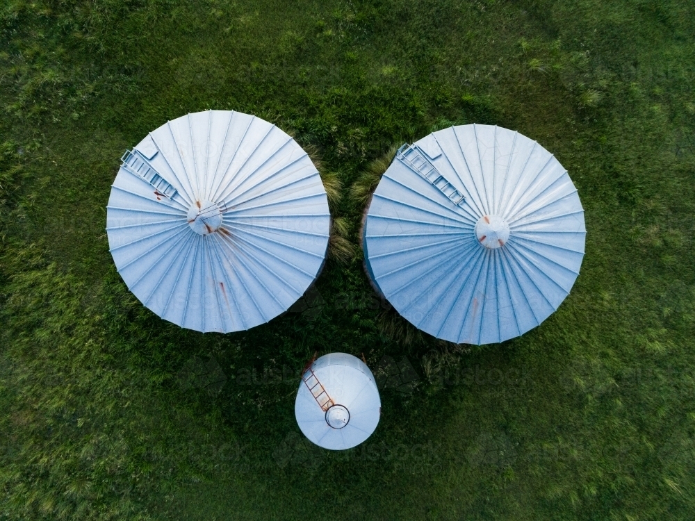 Overhead aerial view of three grain storage silos on a farm - Australian Stock Image