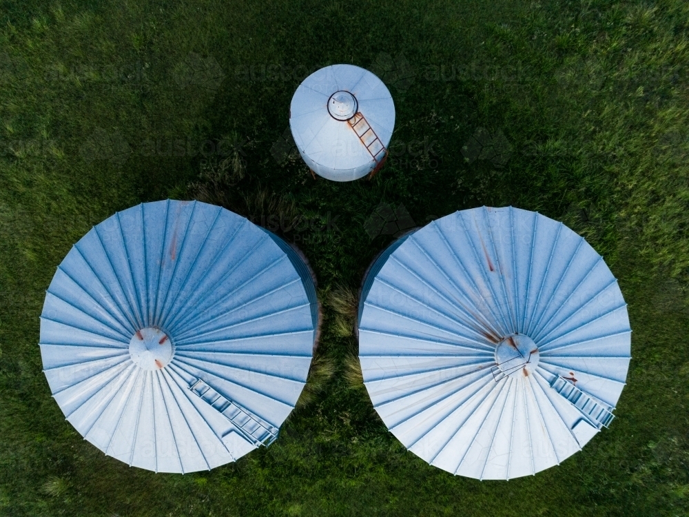 Overhead aerial view of three grain storage silos on a farm - Australian Stock Image