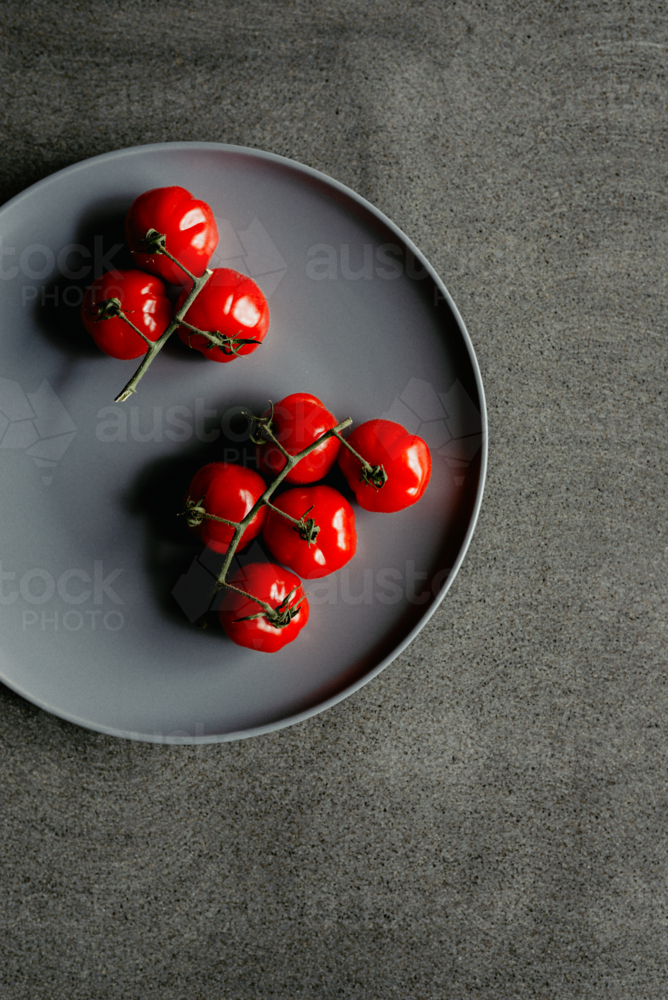 Overhead view of fresh, ripe homegrown vine picked organic heirloom red tomatoes on a plate - Australian Stock Image