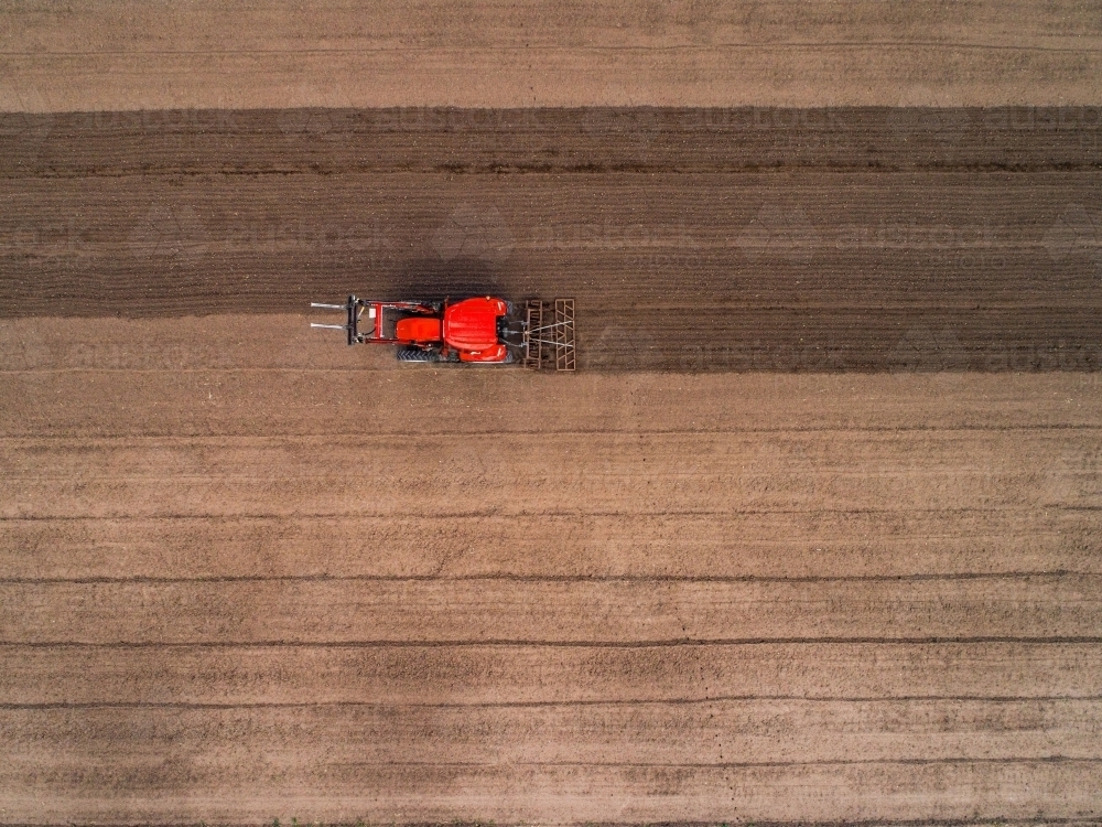 Overhead view of tractor on farm ploughing soil ready for planting new crop in fertile farmland - Australian Stock Image