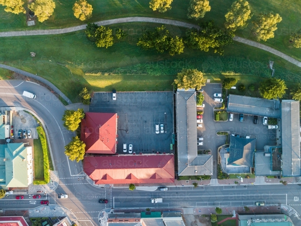 Overhead view of traffic light intersection and shop buildings on main street with park behind - Australian Stock Image