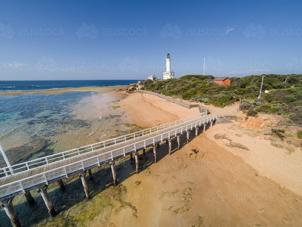 Overlooking a wooden jetty and rocky beach below the lighthouse at Point Lonsdale - Australian Stock Image