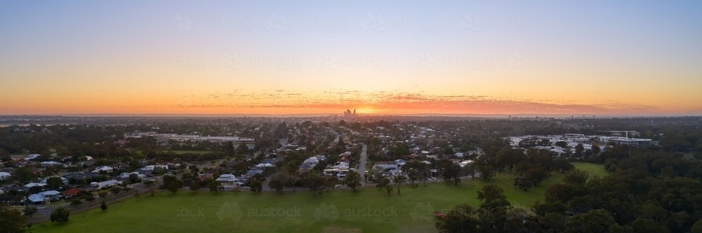 Panoramic aerial view of the sun rising in Perth, Western Australia, with CBD skyline on the horizon - Australian Stock Image