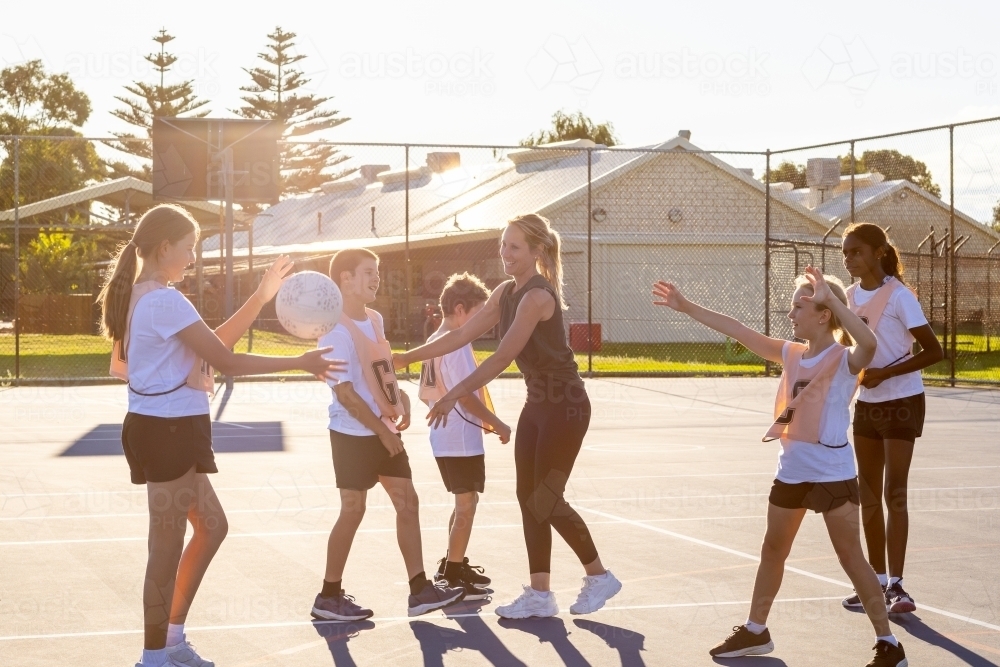 parent coaching kids netball team with boys and girls - Australian Stock Image