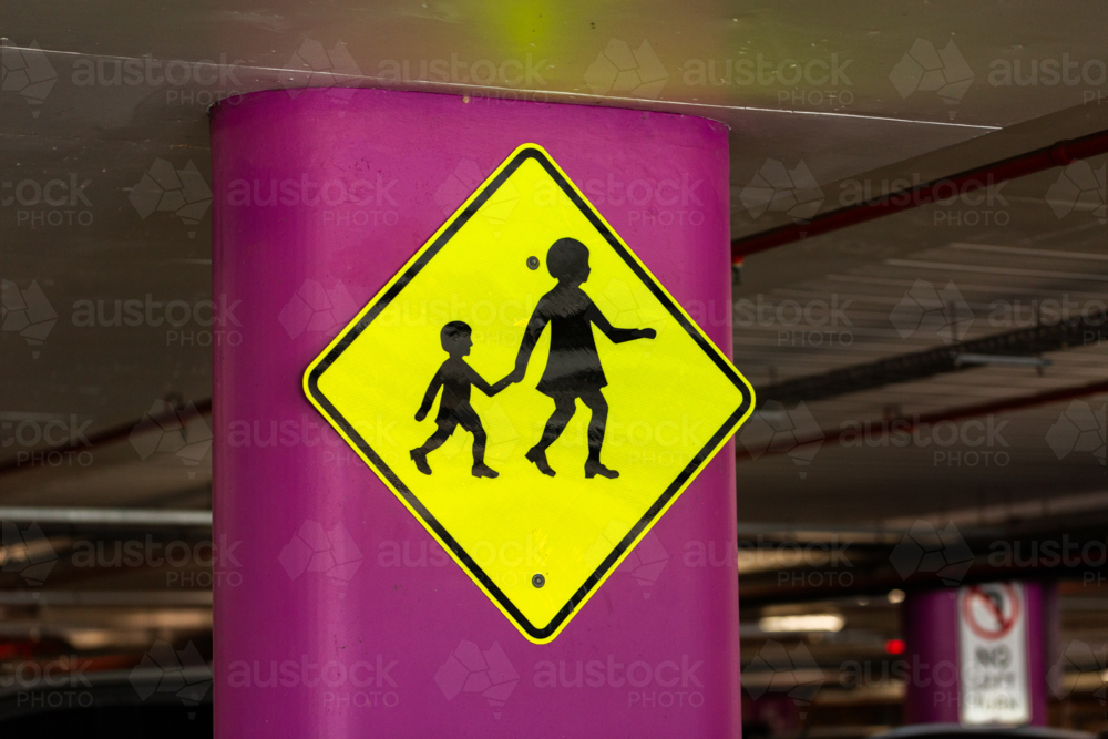 parent holding child hand pedestrian crossing signage in undercover carpark - child safety concept - Australian Stock Image