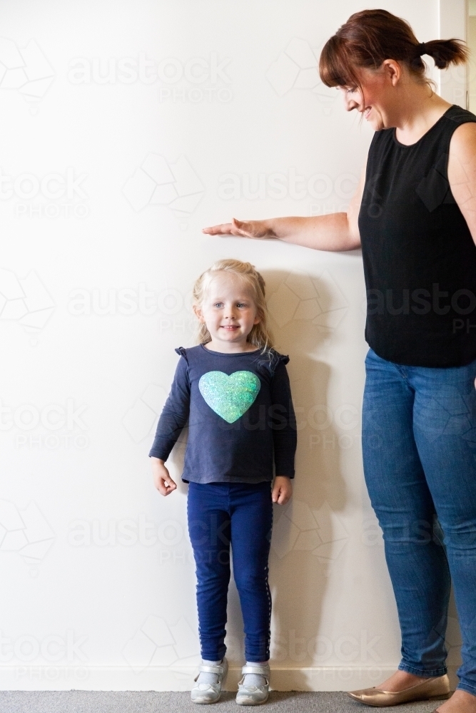 Parent measuring child's height - Australian Stock Image