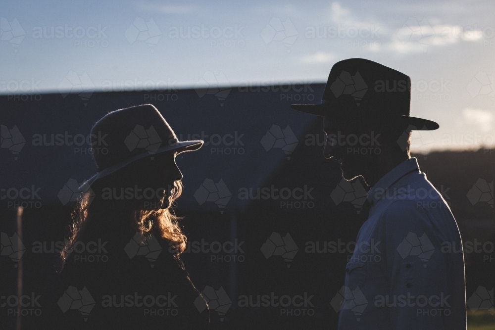 Partial silhouette of a man and woman talking in the evening - Australian Stock Image