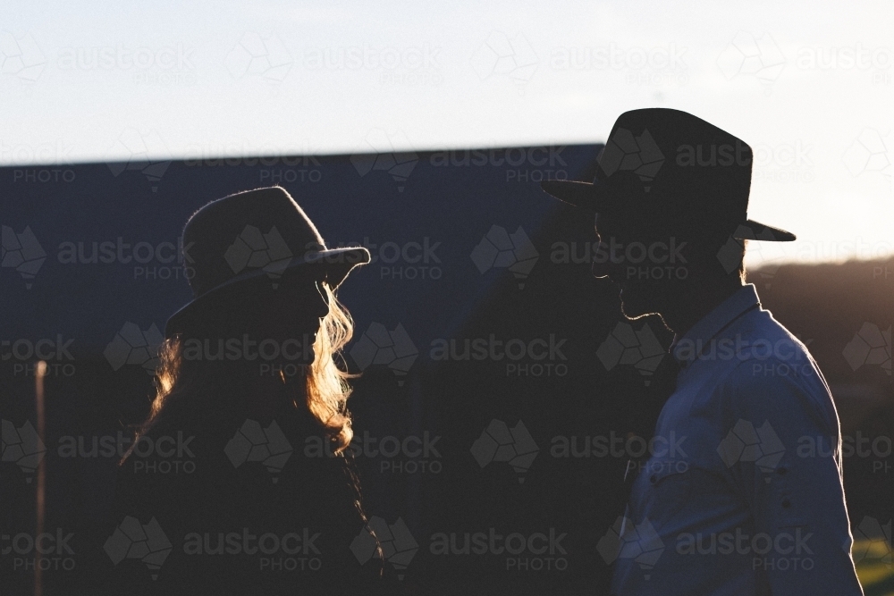 Partial silhouette of a man and woman talking in the evening - Australian Stock Image