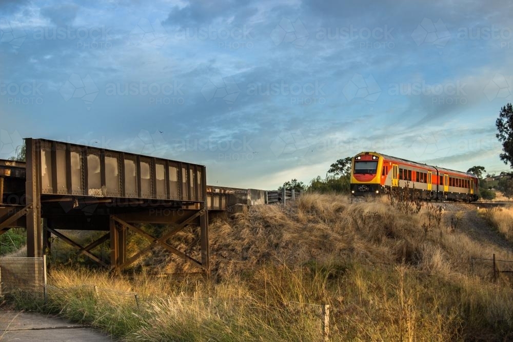 Passenger train about to cross a bridge over the highway - Australian Stock Image