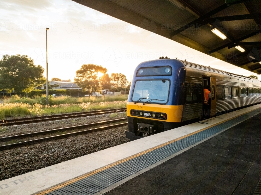 Passenger train coming into statin at sunset - Australian Stock Image