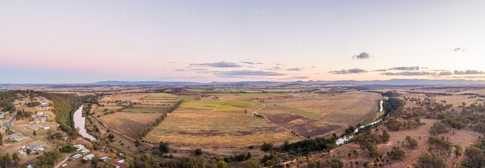 Pastel dusk sky over view of distant farm paddocks and cliff - Australian Stock Image