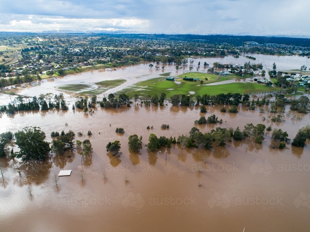 Patch of farmland paddock cut off by floodwater aerial view over flood and river - Australian Stock Image