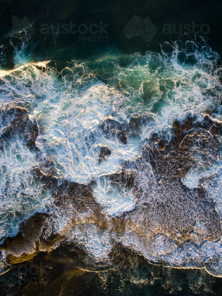 Patterns emerge on an exposed reef after crashing waves recede into the ocean - Australian Stock Image