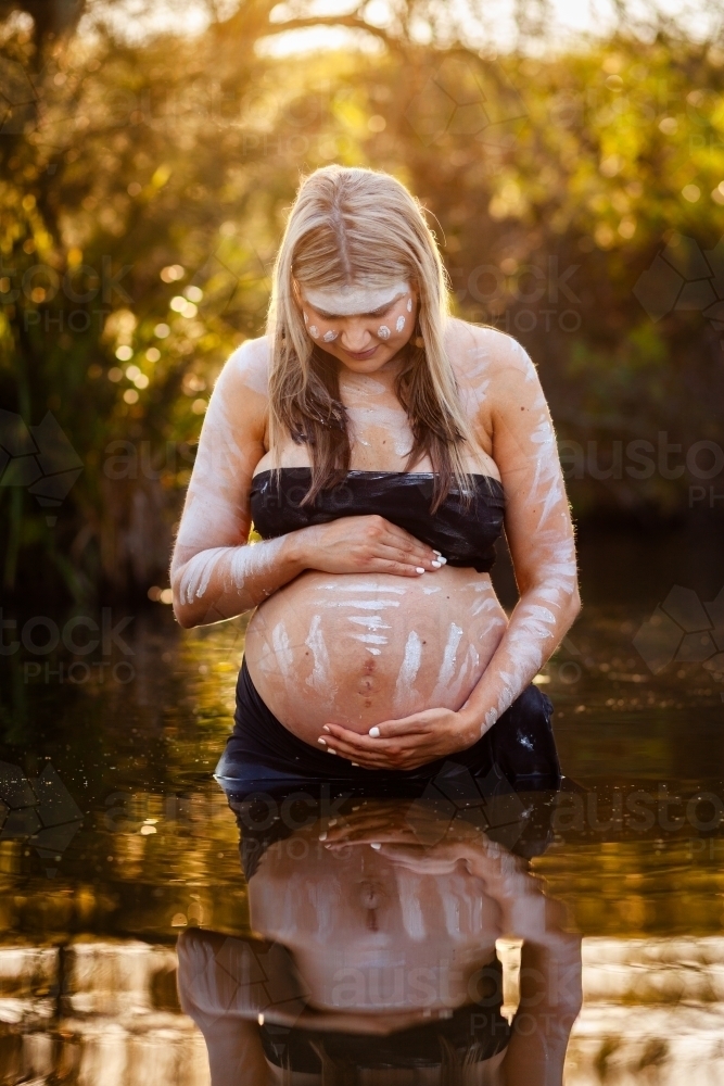 Peaceful scene with pregnant aboriginal woman in still water with reflection - Australian Stock Image