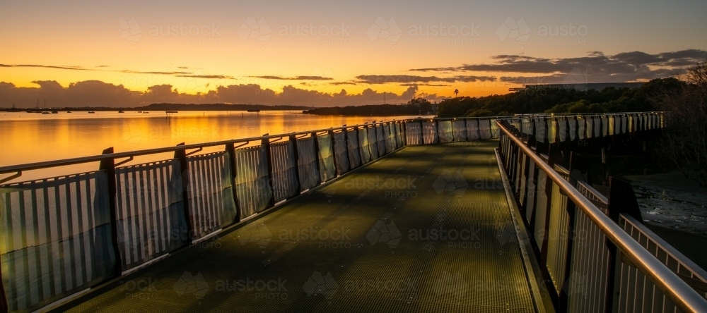 Pedestrian walkway bridge by the bay at sunrise - Australian Stock Image