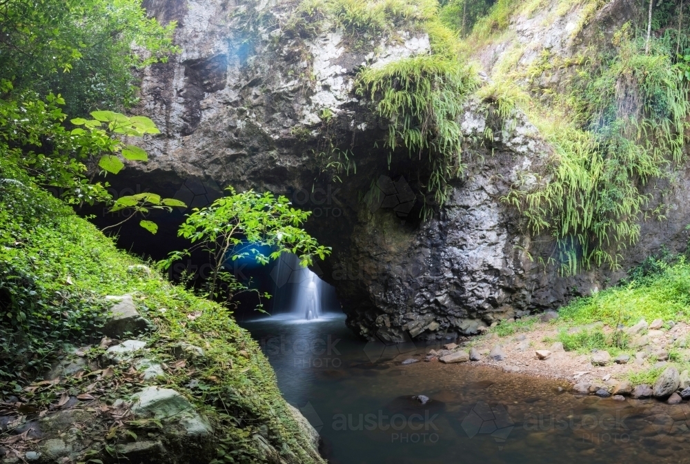 Peering in to a hidden waterfall in a cave - Australian Stock Image