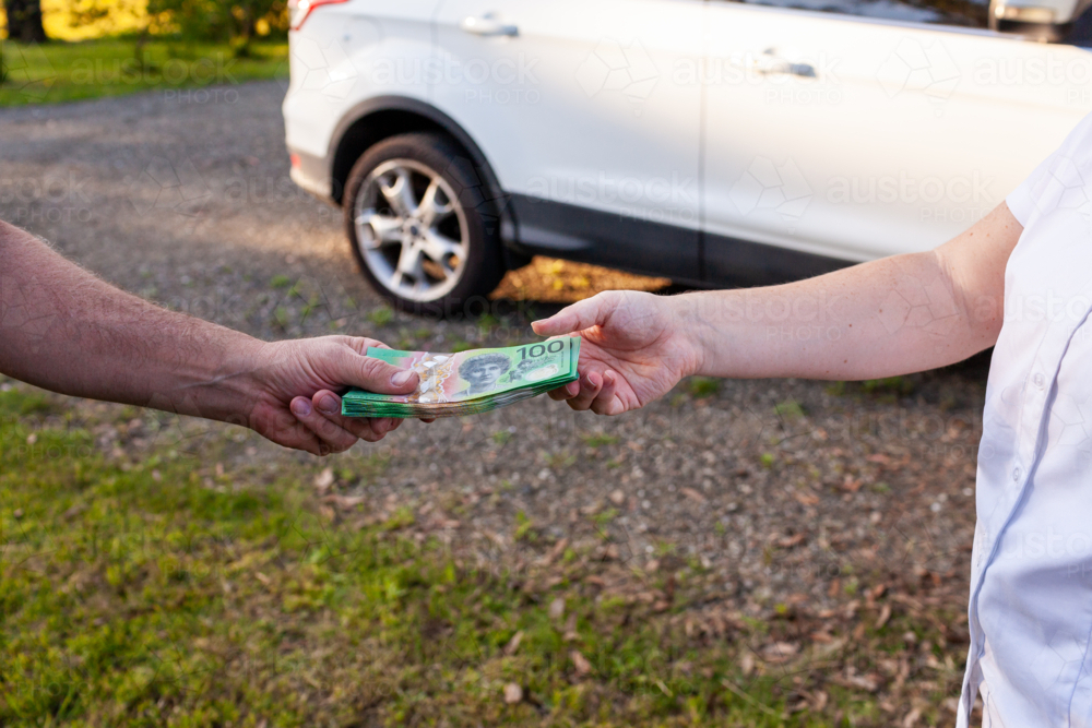 People handing over cash in one hundred dollar notes to pay for car - Australian Stock Image